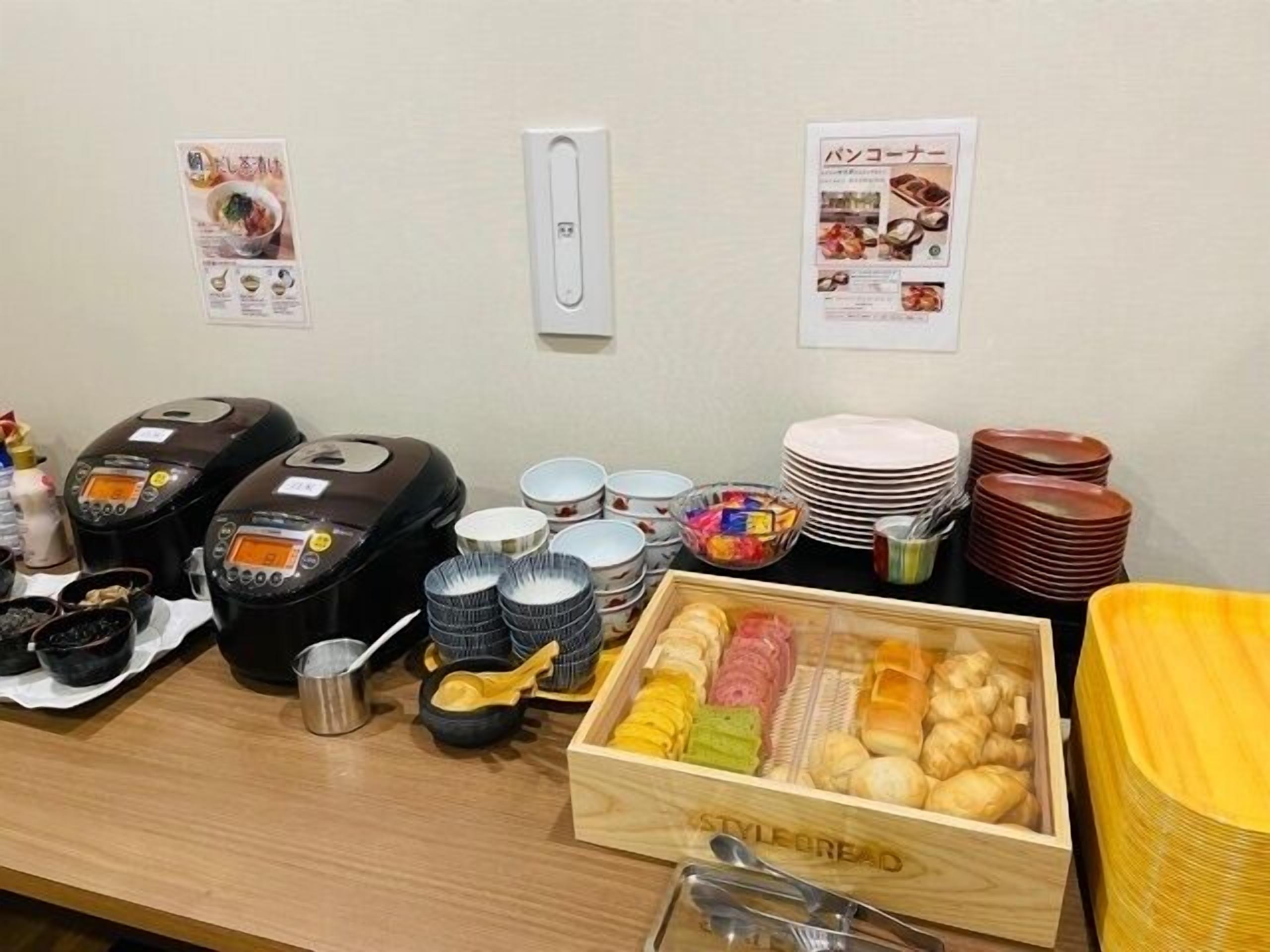 A buffet setup with various food items, serving utensils, and a rice cooker.