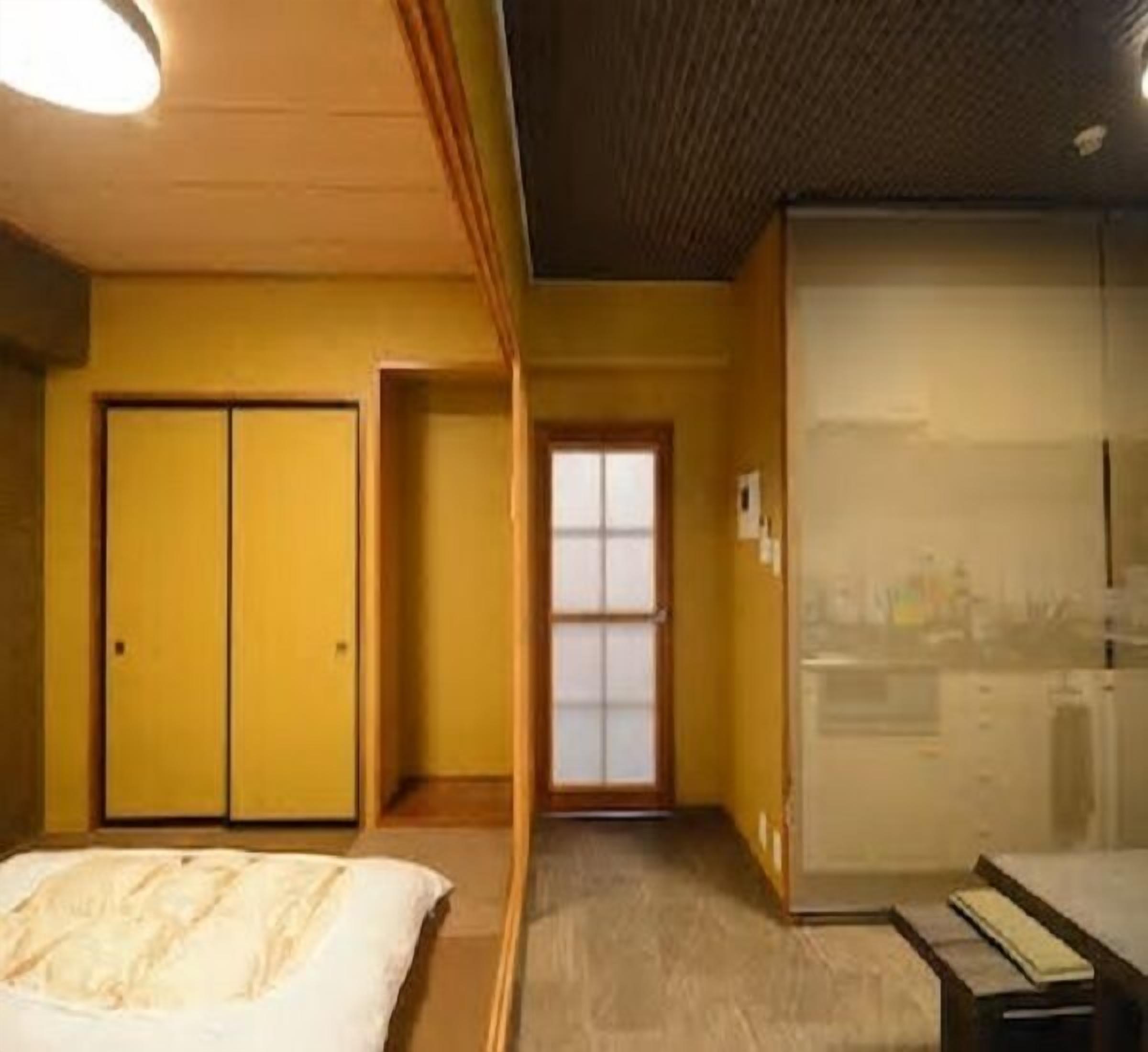 Une pièce comprenant un lit, un bureau, une armoire et une porte coulissante donnant sur une autre pièce.