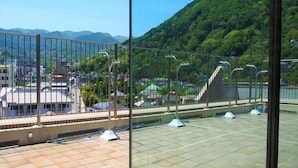 Eine Dachterrasse mit Blick auf einen grünen Hügel und eine Brücke.