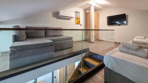 A modern room with a glass railing, a sofa, a flat-screen TV, and a staircase. - B2 - SASHA Loft by SDR (Paralia)