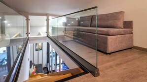 A modern interior with a glass staircase, a sofa, and a wall-mounted air conditioner. - B2 - SASHA Loft by SDR (Paralia)