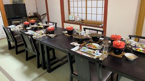 A traditional Japanese dining room with tatami flooring, a low table set for a meal, and a sliding door with a 'No Smoking' sign. - Okukannabe Hutte (Toyooka)