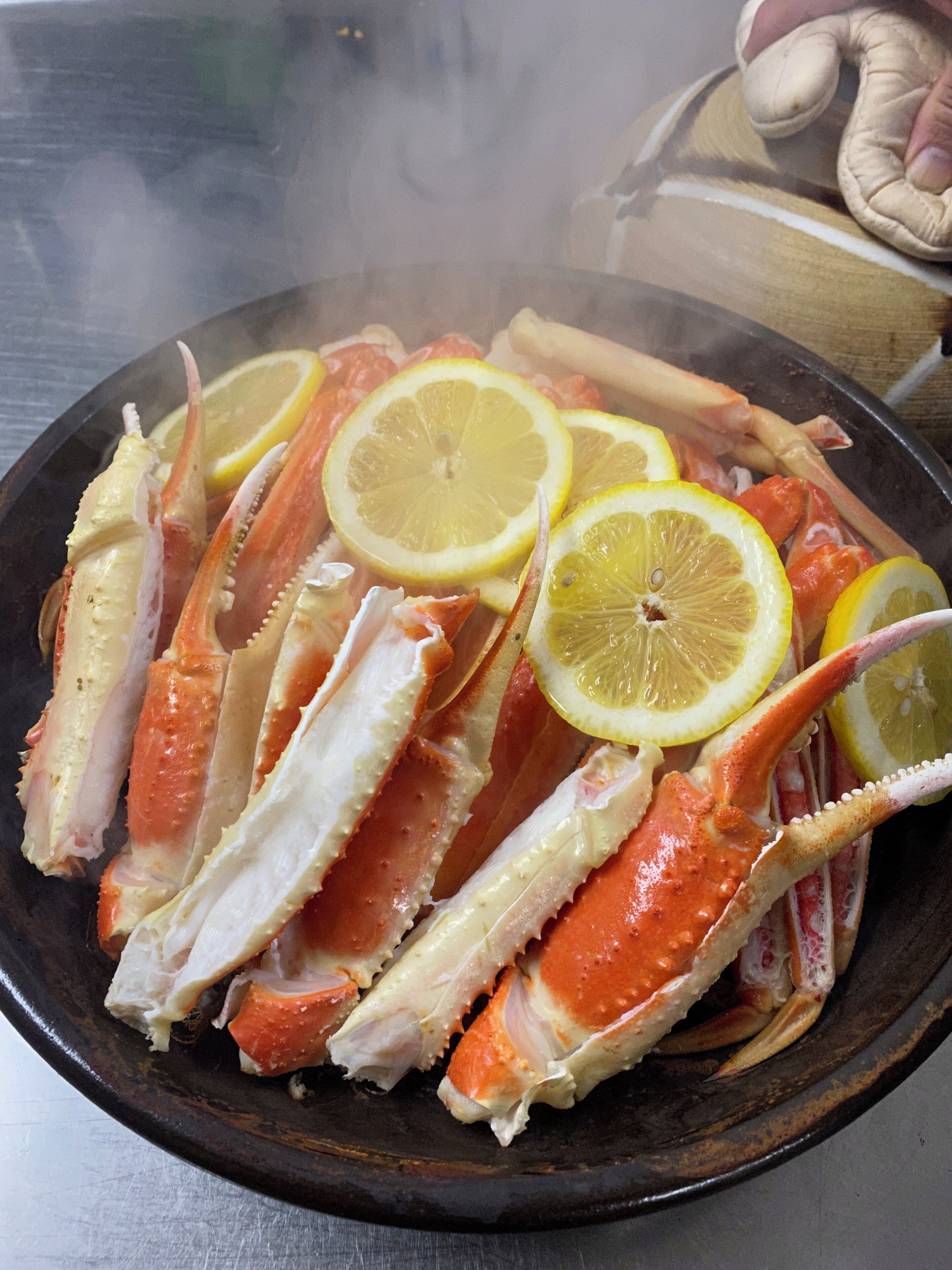 Un plato de patas de cangrejo cocidas con rodajas de limón.