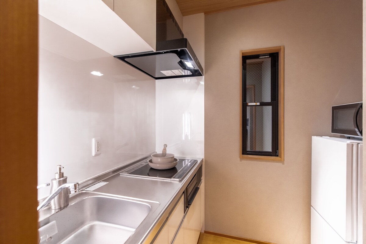 Cozinha moderna com eletrodomésticos de aço inoxidável, uma pia dupla e uma janela sobre o balcão.