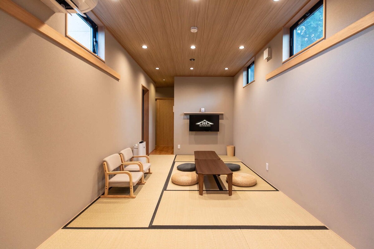 Una habitación tradicional japonesa con suelo de tatami, una mesita baja y asientos.
