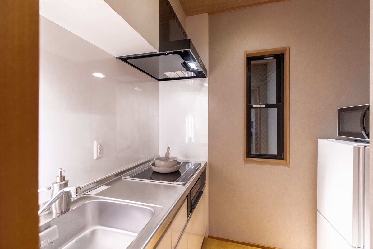 Una cocina moderna con electrodomésticos de acero inoxidable, un lavamanos doble y una ventana sobre la encimera.