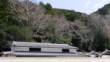 A traditional Japanese building with a tiled roof, surrounded by dense forest.