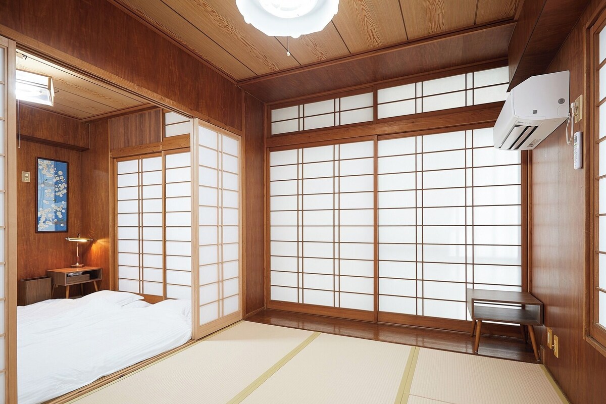Ett traditionellt japanskt rum med tatamimattor på golvet, en säng, ett skrivbord och en stor skjutdörr av rispapper (shoji).