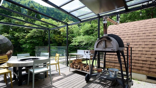 Un patio al aire libre con horno de pizza, zona de estar y un brasero.