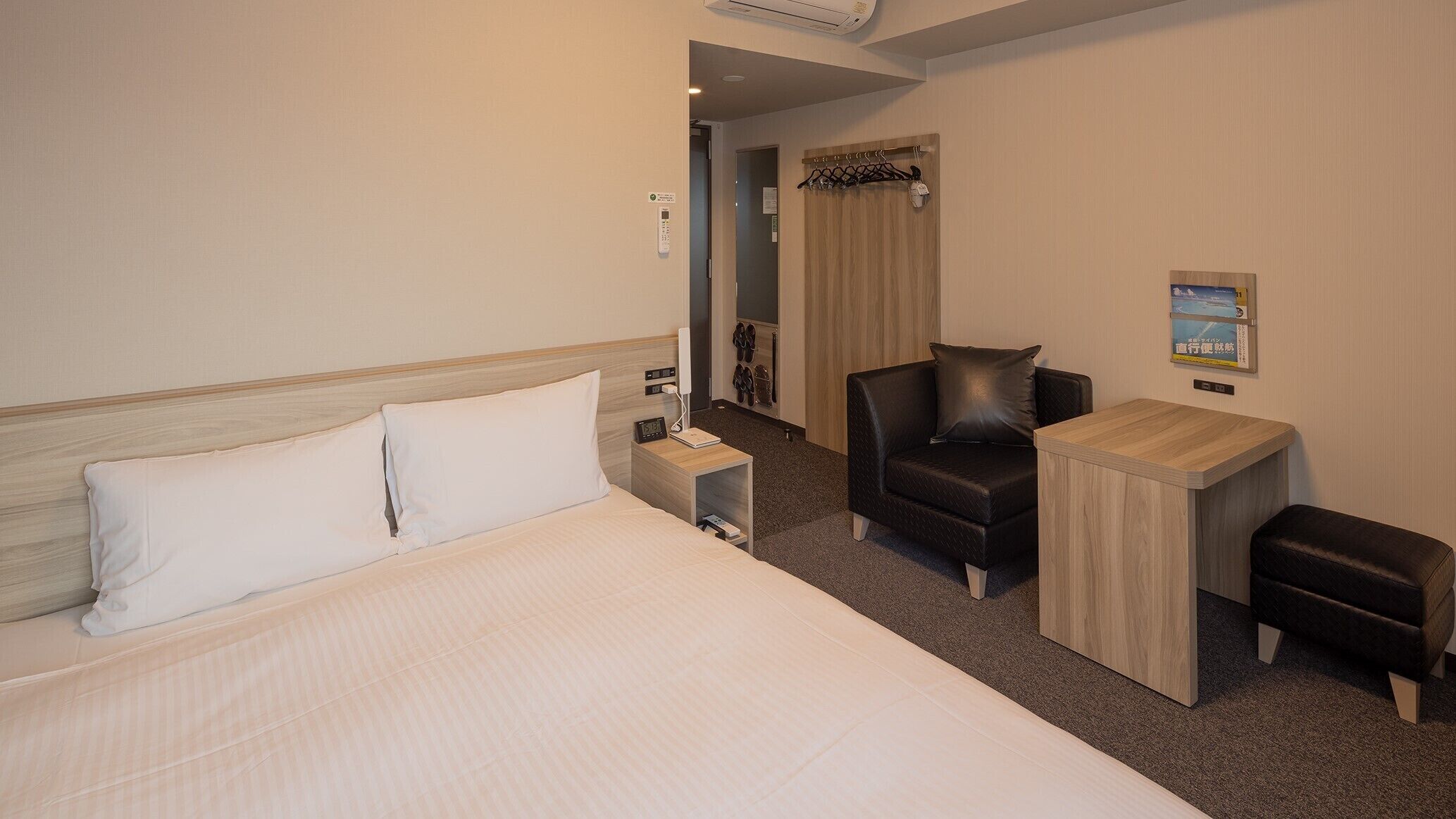 A hotel room with a bed, a desk, a chair, and a small table.