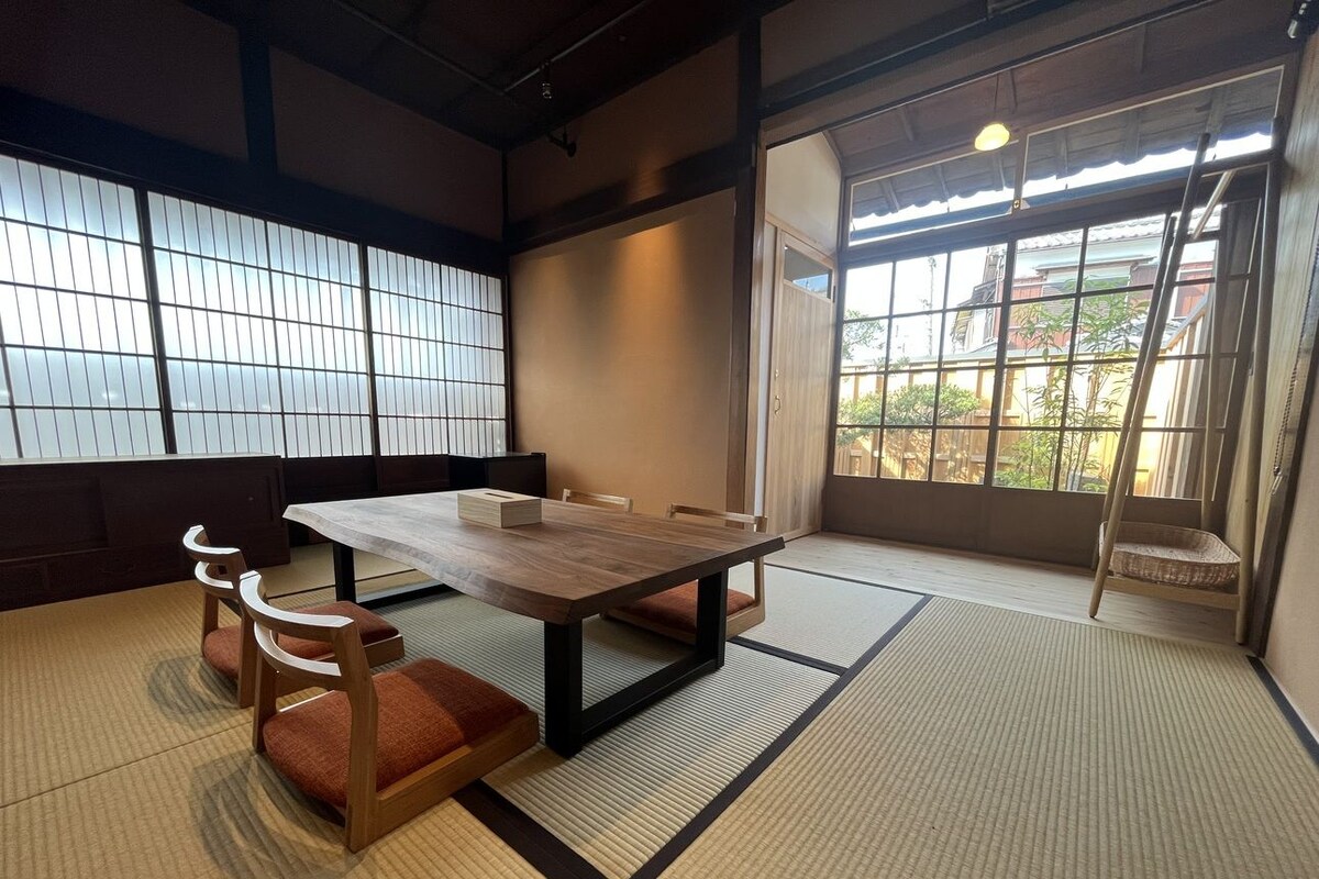 Una stanza tradizionale giapponese con pavimento in tatami, un tavolino in legno e pannelli scorrevoli shoji.
