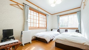 A room with two beds, a TV, a radiator, and a window with curtains. - Pension Mascot (Tsumagoi)