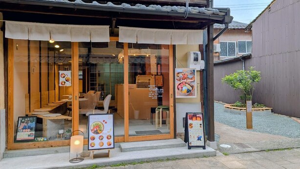 Un restaurante con una decoración tradicional japonesa, fachada de madera y un pequeño jardín.