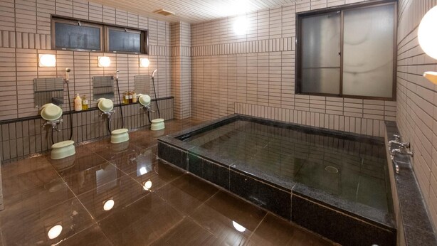 A modern bathroom with a large bathtub, multiple sinks, and a tiled wall. - Ubeshimakan (Wakasa)