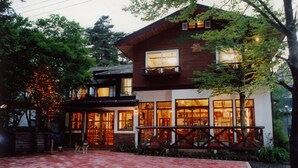 A two-story house with large windows, a balcony, and a dog in the yard.