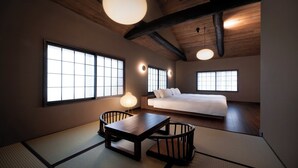 A traditional Japanese-style room with tatami flooring, a low bed, and a table with chairs.