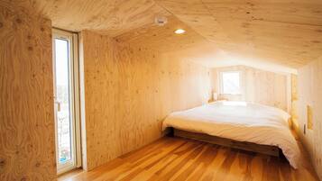 Une pièce aux murs en bois et au plafond en pente, avec un lit et une fenêtre.