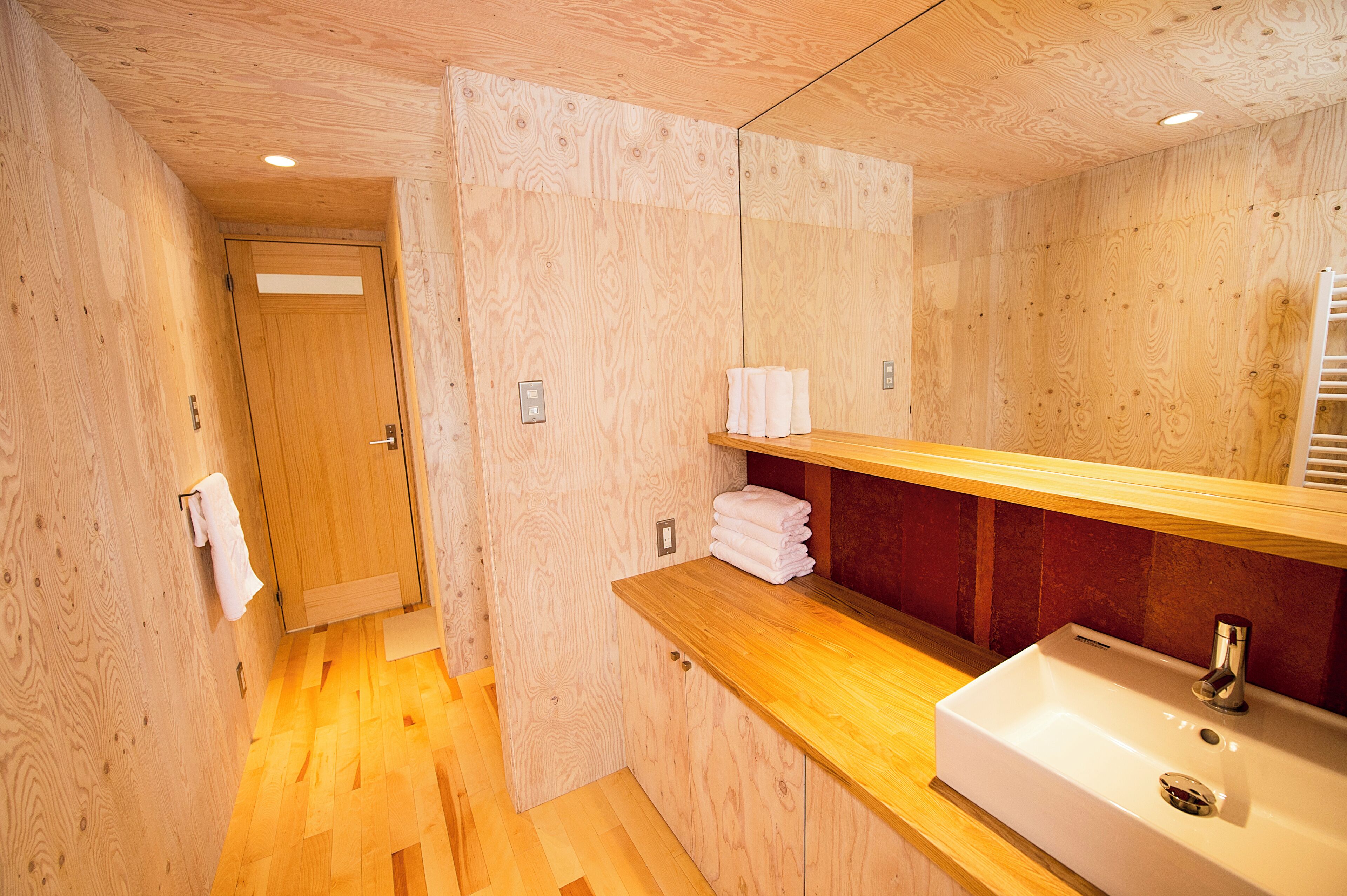 Un intérieur en bois avec un évier, un porte-serviettes et une porte.