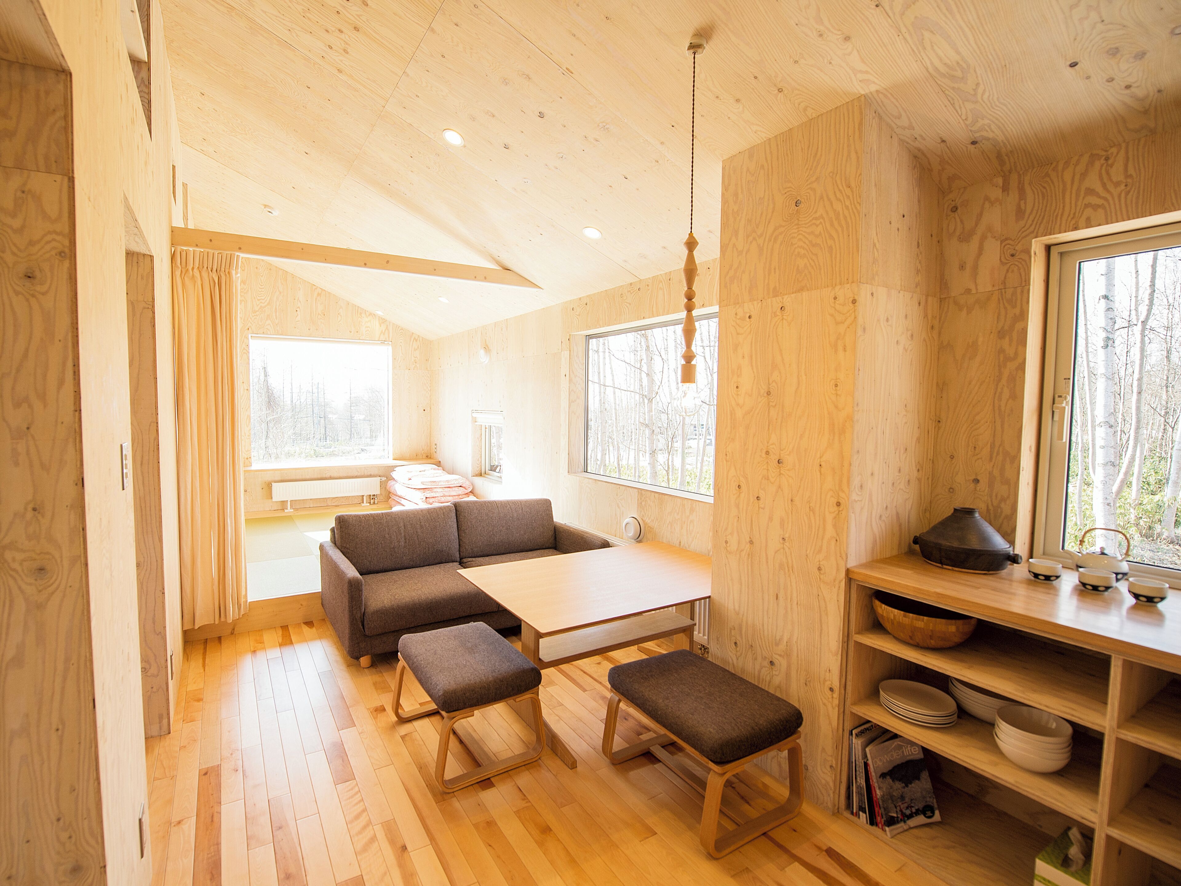 Un intérieur en bois comprenant un canapé, un banc, une table et des étagères.