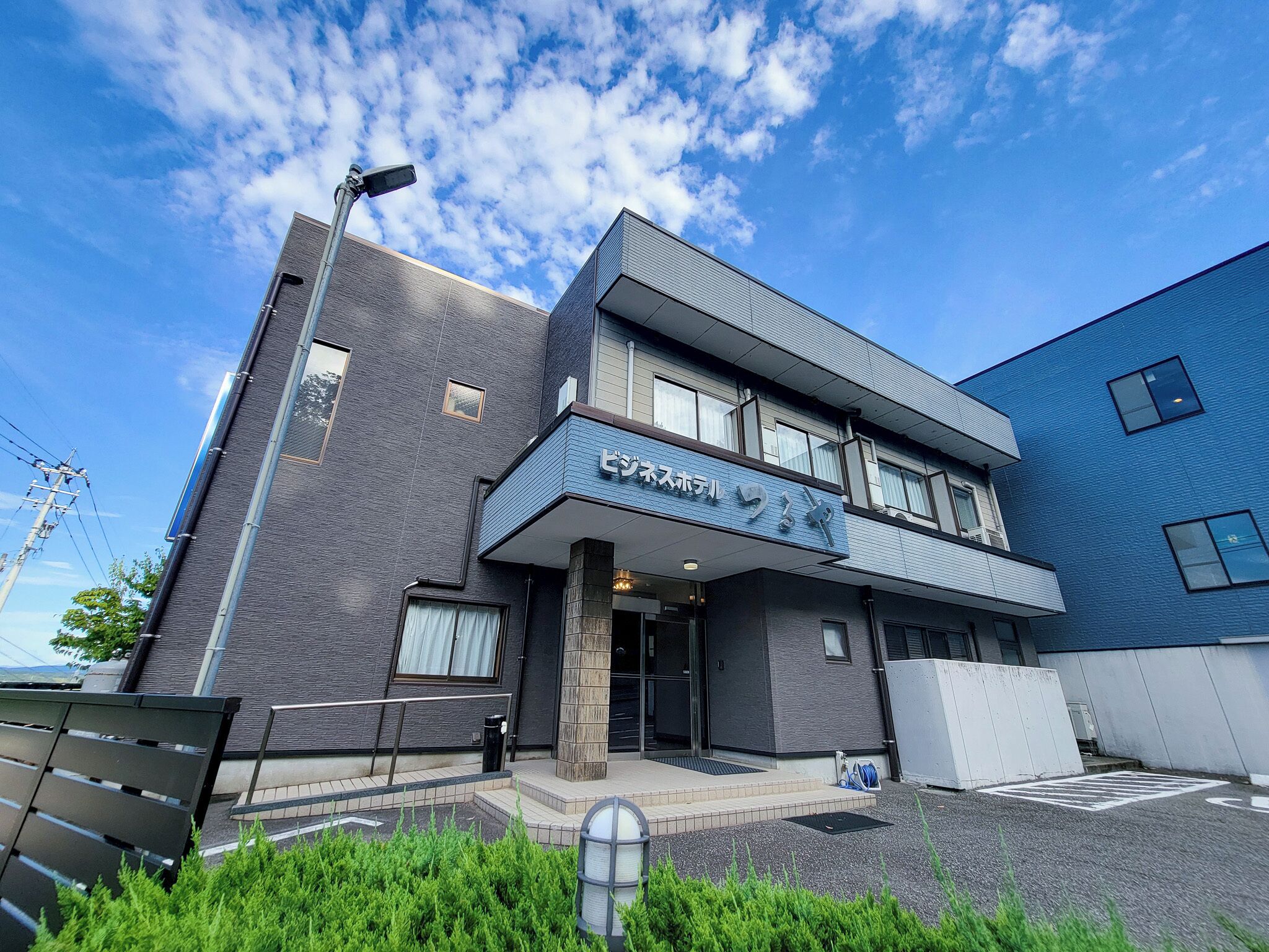 A modern building with a flat roof, large windows, and a sign indicating it is a hotel.