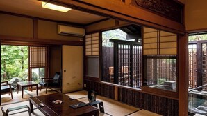 A traditional Japanese room with tatami flooring, sliding doors, and a view of a garden.