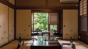 A traditional Japanese room with tatami flooring, sliding doors, and a view of a garden.