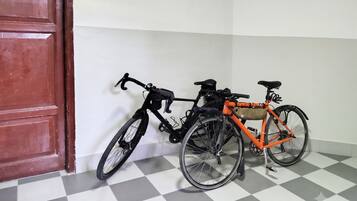 A room with a checkered floor, a red door, and two bicycles leaning against the wall.