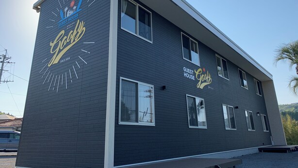 A two-story building with a dark facade, multiple windows, and a logo on the side.