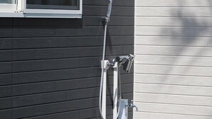 A residential exterior with a window, a hose, and a water spout.