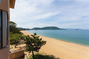 Ein Strand mit freiem Blick auf das Meer und ferne Berge.