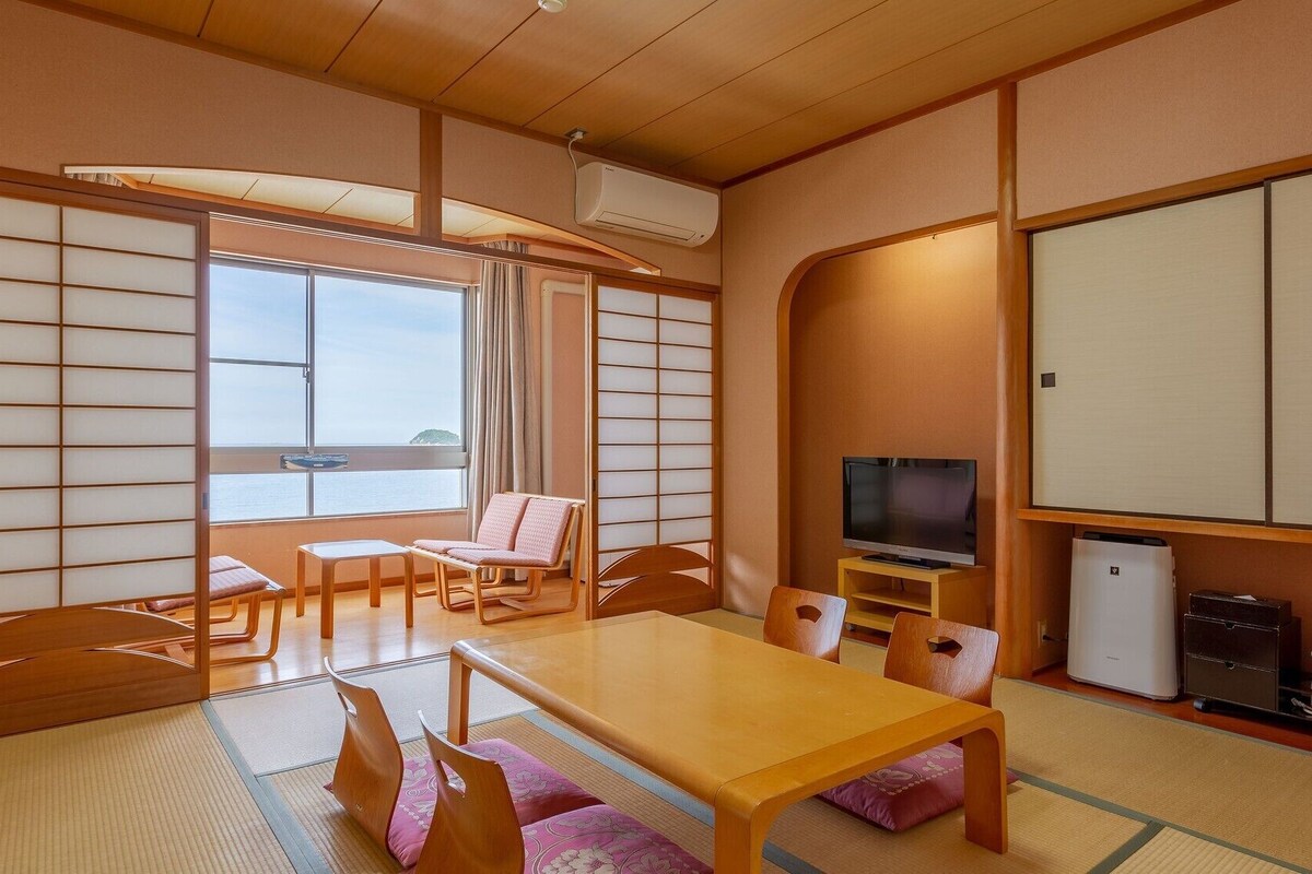 Une pièce de style japonais traditionnel, avec un sol recouvert de tatamis, une table basse et un téléviseur.