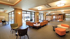 A spacious lobby with seating areas, a reception desk, and large windows allowing natural light.