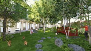 A landscaped garden with a red bridge, stone pathways, and a variety of trees.