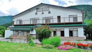 A two-story building with a balcony on the upper floor, surrounded by greenery and flowers. - Shinshu Norikura Kogen Onsen Ryokuzansou (Matsumoto)