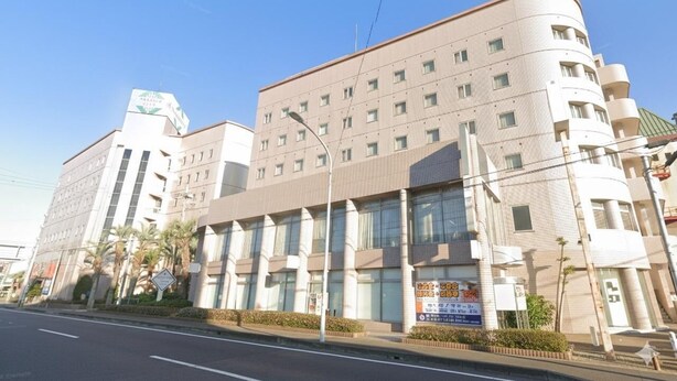 A multi-story building with a curved facade, large windows, and a sign indicating a medical facility. - Hotel Sunmall (Asahi)