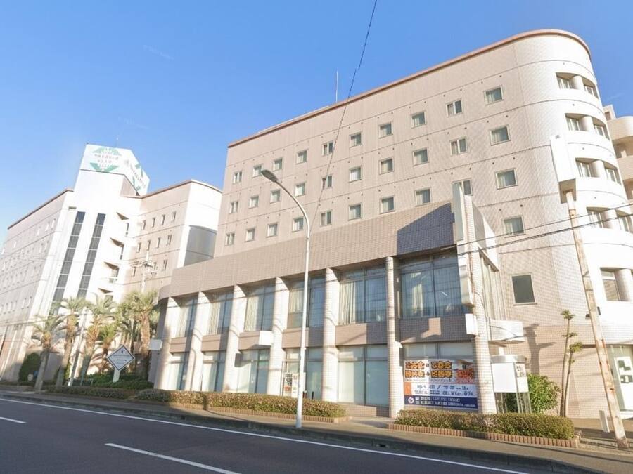 A multi-story building with a curved facade, large windows, and a sign indicating a medical facility.
