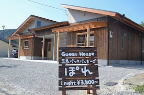A wooden guest house with a sign indicating a 1-night stay price of ¥3,500.