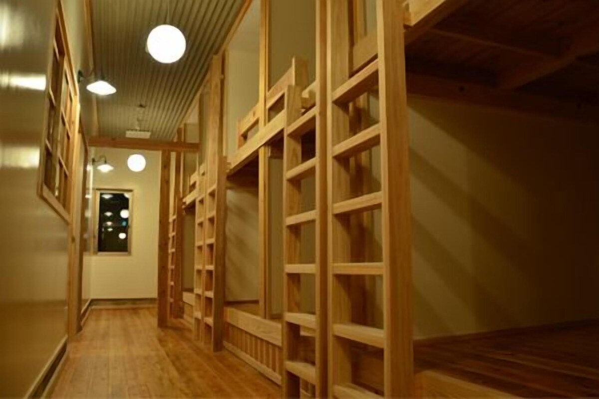 Un couloir aux murs lambrissés, doté d’un plancher en bois et d’un plafond pourvu d’un éclairage encastré.