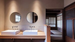 Un baño moderno con dos lavamanos, espejos redondos y una puerta corredera tradicional japonesa.