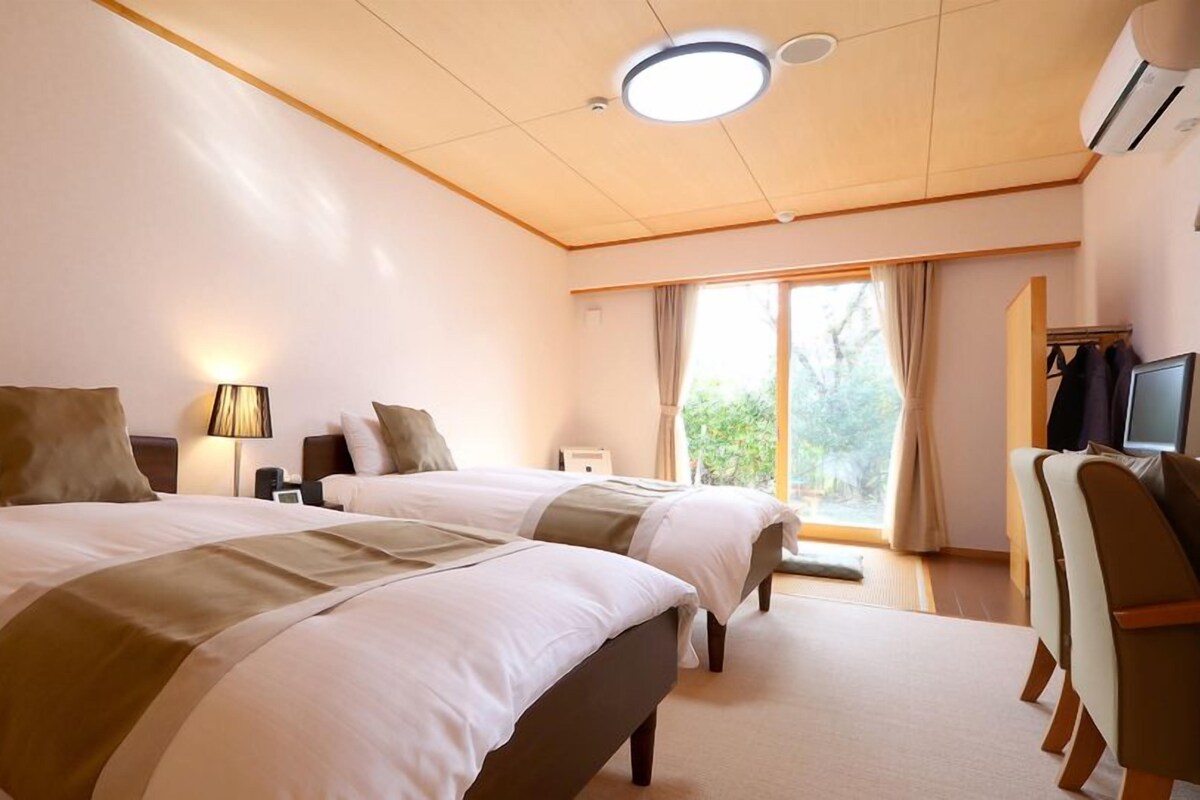 Een hotelkamer met twee bedden, een bureau, een stoel en een televisie.