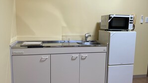 A kitchenette with a microwave, sink, and cabinets.