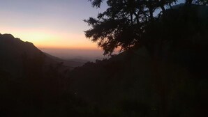 Paisaje montañoso al atardecer con vistas a colinas distantes.