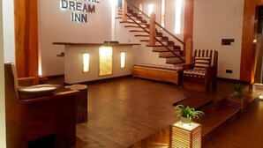 Un área de recepción con una escalera, muebles de madera y un letrero que dice 'LEISURE DREAM INN'.