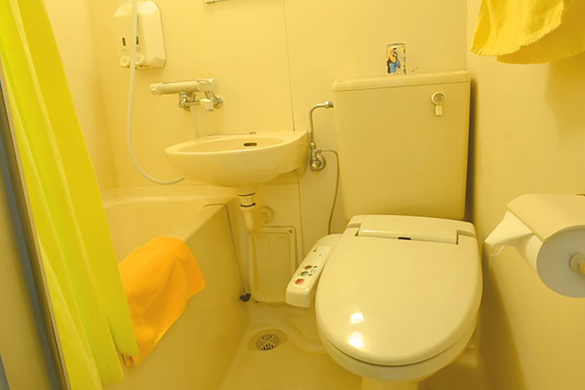 A small bathroom with a toilet, sink, and toilet paper holder.