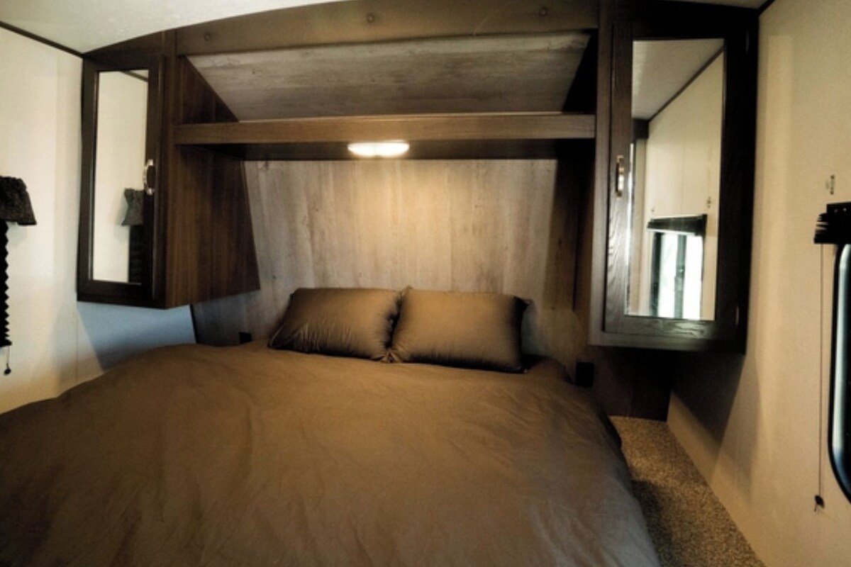Um interior acolhedor com uma cama, uma janela e um espelho.