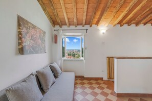 Una stanza con soffitto in legno, un divano con cuscini, una finestra vista e pavimento piastrellato.