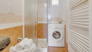 Ein Badezimmer mit Dusche, Toilette und Waschmaschine.