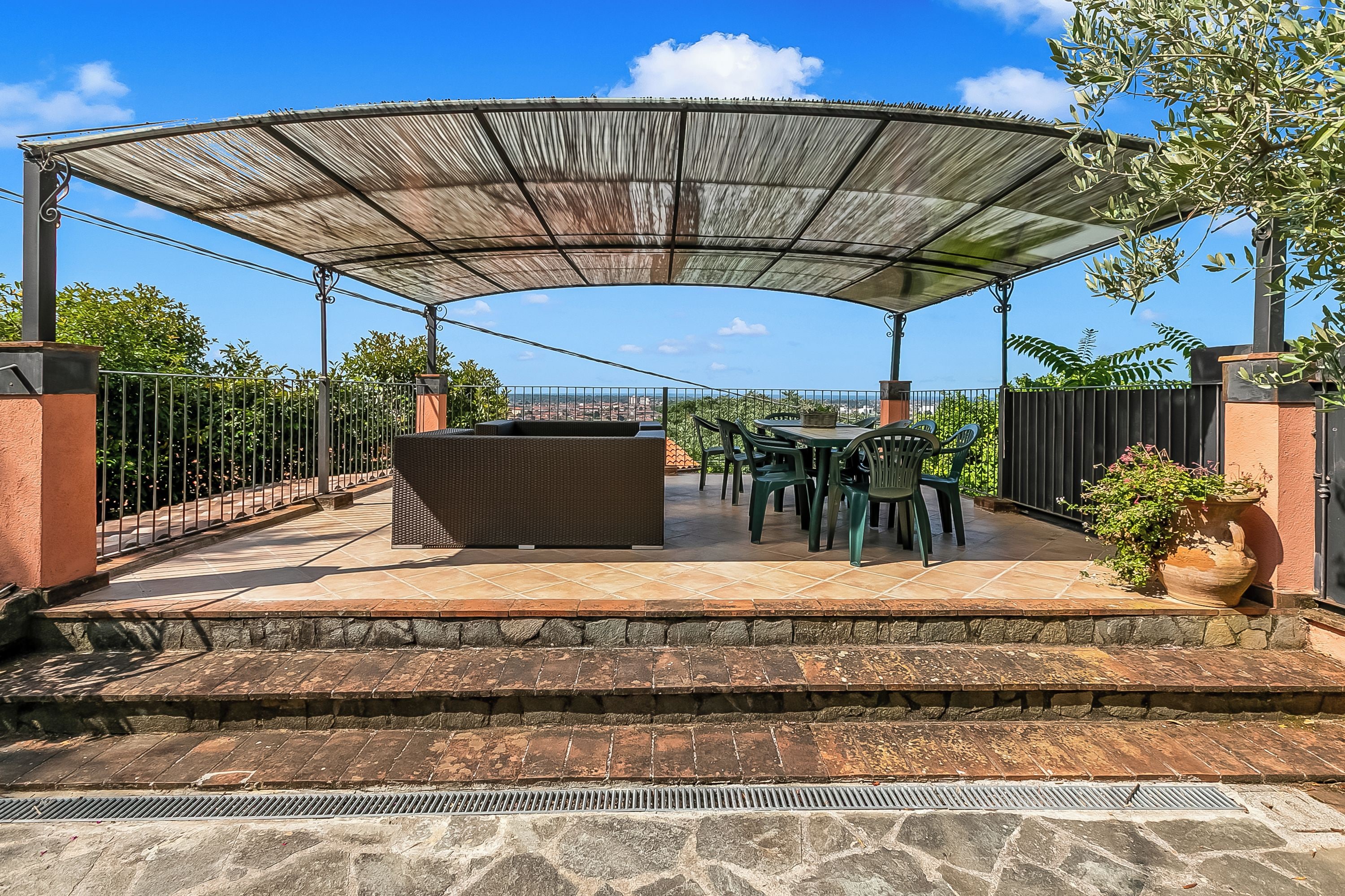 An outdoor patio with a covered seating area, stone steps, and a view of the cityscape.