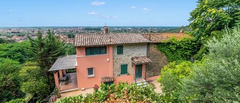 A hillside villa with a stone facade, a terrace, and a view of the surrounding landscape.