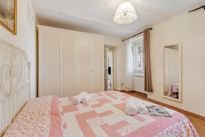 Una camera da letto con un letto, un armadio, uno specchio e un lampadario.